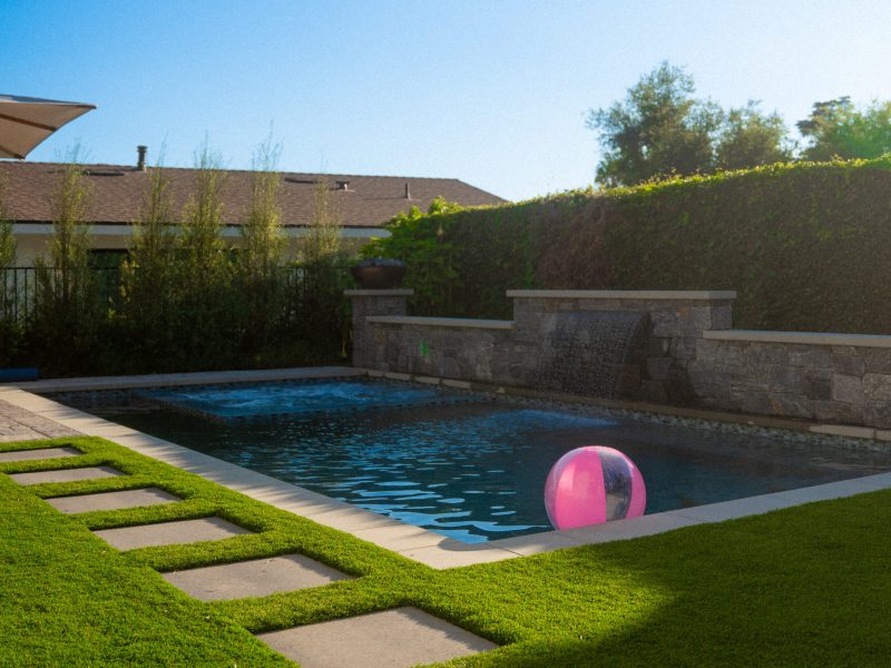 Completed pool with stepping stones through turf and stone scupper wall